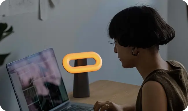 Woman working on laptop with Osin lamp beside her
