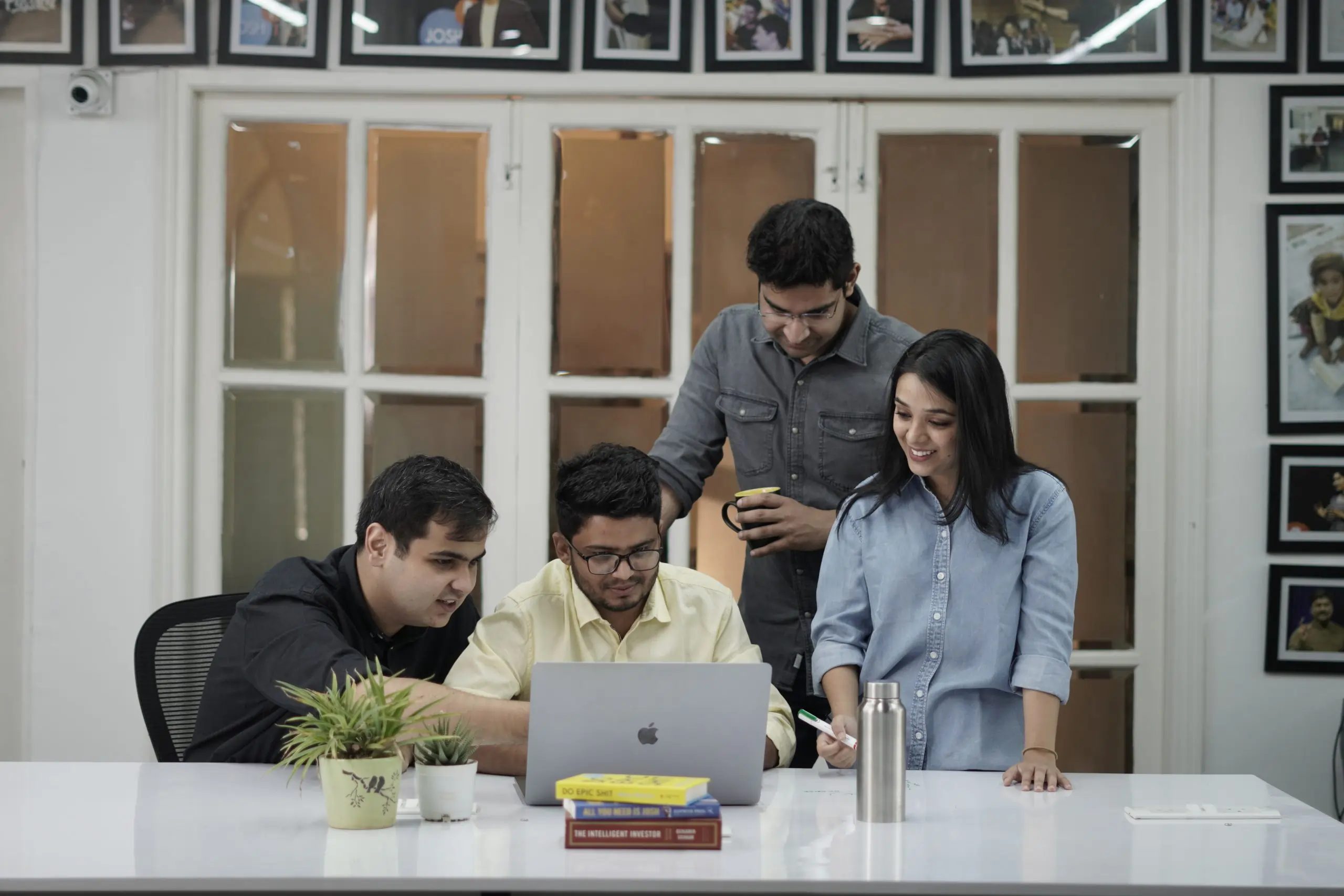 four people looking at laptop